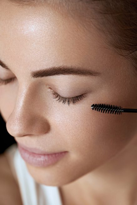 Woman applying black mascara on eyelashes